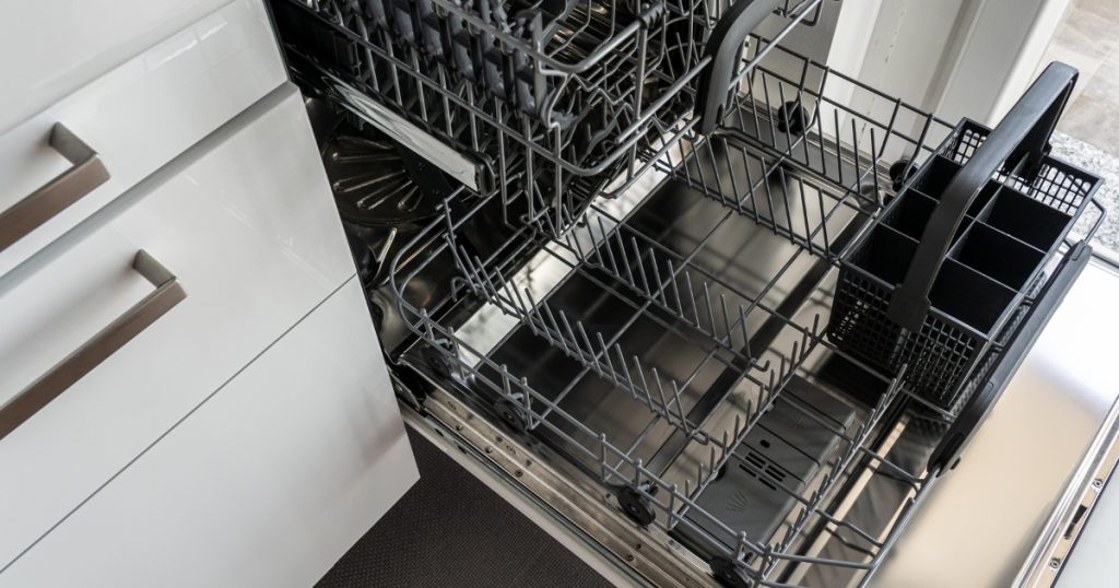 Open dishwasher with empty racks, highlighting potential drainage issues. Common causes of a dishwasher not draining properly include clogged filters, blocked drain hoses, faulty drain pumps, or a malfunctioning check valve. Learn how to troubleshoot and fix dishwasher drainage problems effectively