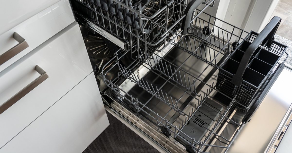 Open dishwasher with empty racks, highlighting potential drainage issues. Common causes of a dishwasher not draining properly include clogged filters, blocked drain hoses, faulty drain pumps, or a malfunctioning check valve. Learn how to troubleshoot and fix dishwasher drainage problems effectively